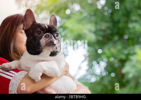 Jeune femme tenant un bouledogue français sur les bras dans un parc public avec espace de copie. Extérieur avec concept animal de compagnie. Banque D'Images