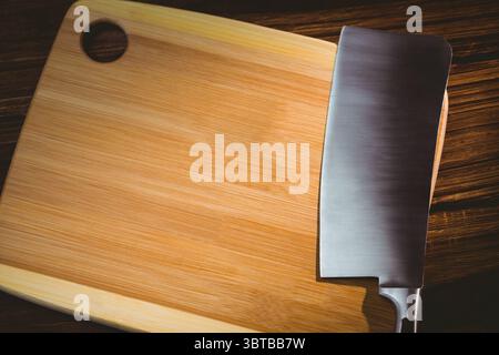 Grand couteau métallique et planche à découper sur plancher en bois Banque D'Images