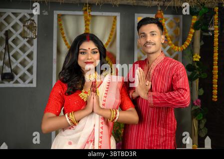 Portrait d'un homme habillé en pyjama kurta et d'une belle femme indienne portant un saree traditionnel, tous deux ornés de bijoux en or, debout avec th Banque D'Images