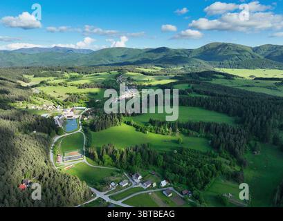 Paysage serein avec le village rural. des prairies verdoyantes hurlantes, des maisons traditionnelles et des montagnes alpines pittoresques sous un sk bleu clair Banque D'Images