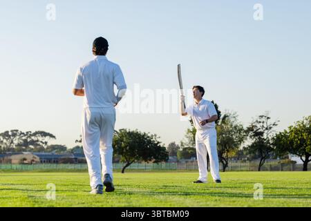 Divers joueurs de cricket masculins pratiquant le batteur en uniformes sur le terrain d'herbe avec espace de copie de chauve-souris en bois Banque D'Images