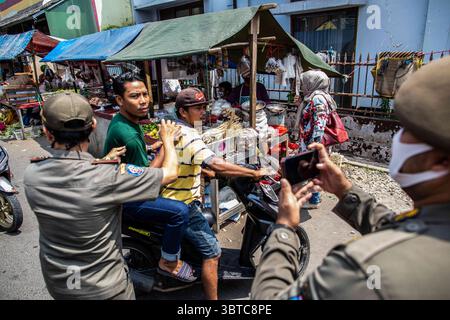 1 septembre 2020, Pamulang, Banten, Indonésie : Tangerang Sud, Bante, Indonésie, 01 septembre 2020 : une équipe de l'unité de police de la fonction publique arrête un vélo avec des passagers qui n'utilisent pas de masque et de casque. Tangerang Sud : L'unité de police de la fonction publique avec l'administration de la santé du Tangerang Sud a tenu une supervision diciplinaire du port du masque et du test rapide au marché Reni, Pamulang Sud Tangerang. Avec New normal appliqué en Indonésie, principalement le protocole de santé de porter un masque, la distanciation sociale, éviter le rassemblement dans les lieux publics devenant moins appliqué causant le nombre de propagation du virus corona en Indonésie augmentation Banque D'Images