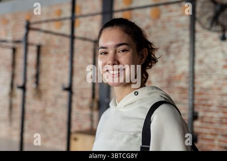 Femme debout dans le gymnase tenant des sangles de sac à dos près des barres de traction et des boîtes plyométriques, espace de copie Banque D'Images