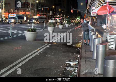 30 août 2020, New York, New York, États-Unis : les rues de New York sont de plus en plus sales et les ordures débordent partout dans la ville qui traverse une crise budgétaire sans précédent. Alors que Donald Trump a annoncé un defund de 7 milliards de dollars d’aide fédérale à la ville, le Département de l’assainissement (DSNY) a été contraint de couper 106 millions de dollars de son budget de fonctionnement durant l’été. Un homme jette les eaux usées de son camion de nourriture dans les rues éparpillées à proximité de Times Square. Les corbeilles d'angle ne seront plus ramassées le dimanche, et il y aura moins de camions effectuant des ramassages sur le wee Banque D'Images