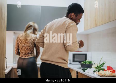 Couple diversifié préparant un repas ensemble dans une cuisine moderne Banque D'Images