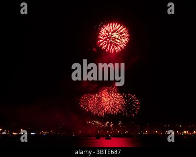 Feux d'artifice rouges explosant dans le ciel nocturne au-dessus de saint-sébastien, espagne, pendant la célébration de la Semana grande Banque D'Images