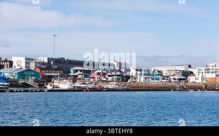 Reykjavik, Islande - 4 avril 2017 : scène portuaire tranquille avec des bateaux amarrés avec des bâtiments vibrants en arrière-plan sur un ciel bleu vif Banque D'Images