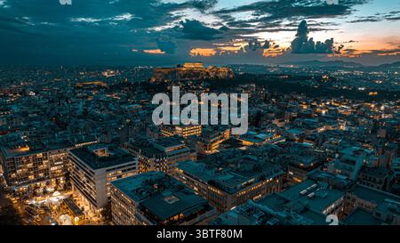 Vue aérienne nocturne d'Athènes, Grèce, avec l'Acropole illuminée et un ciel de coucher de soleil spectaculaire en arrière-plan. Banque D'Images