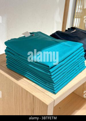 Chemises turquoise pliées sur l'étagère de vente au détail, pile soignée avec le contraste Earth-Tone Banque D'Images