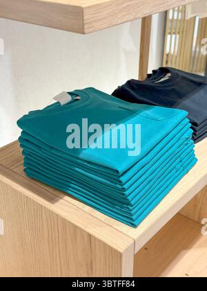 Chemises turquoise pliées sur l'étagère de vente au détail, pile soignée avec le contraste Earth-Tone Banque D'Images