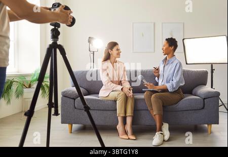 Deux jeunes blogueuses podcasters discutent ensemble et tournent des vidéos en direct en studio. Banque D'Images