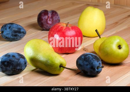 Poires mûres sucrées, pommes et prunes sur une table en bois clair gros plan Banque D'Images