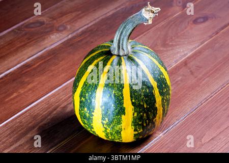 Une petite citrouille mûre et douce se trouve sur une table en bois brun gros plan Banque D'Images