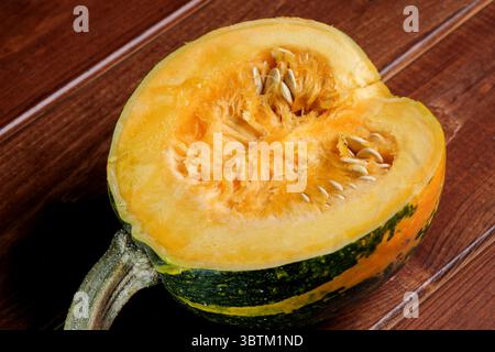 Une petite citrouille mûre et douce se trouve sur une table en bois brun gros plan Banque D'Images