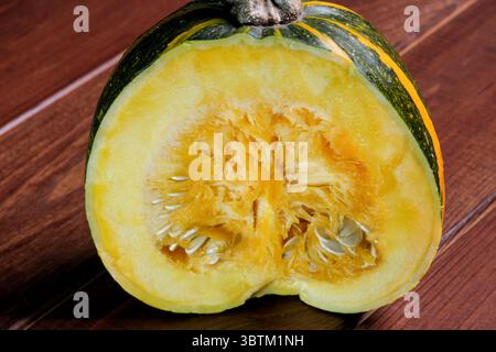 Une petite citrouille mûre et douce se trouve sur une table en bois brun gros plan Banque D'Images