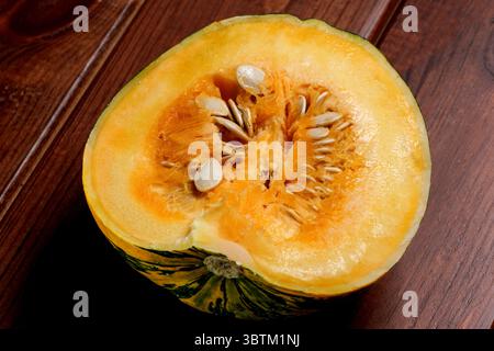 Une petite citrouille mûre et douce se trouve sur une table en bois brun gros plan Banque D'Images