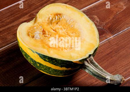 Une petite citrouille mûre et douce se trouve sur une table en bois brun gros plan Banque D'Images