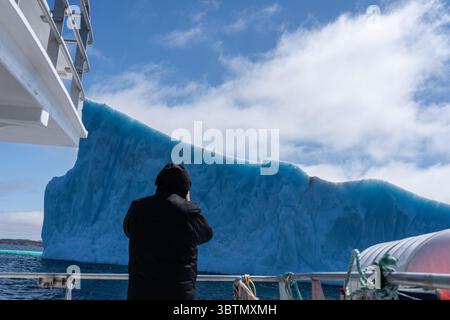Vue arrière d'un homme prenant une photo d'un iceberg depuis un bateau, Terre-Neuve, Terre-Neuve-et-Labrador, Canada Banque D'Images