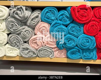 Serviettes roulées en rangées multicolores, présentoir sur étagère avec texture douce harmonieuse Banque D'Images