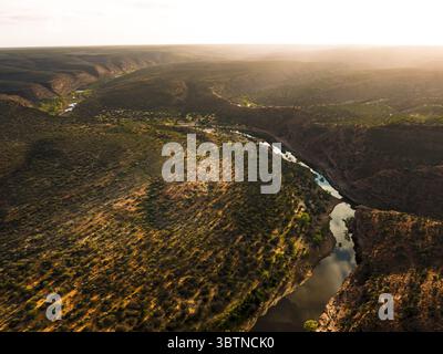 Vue aérienne de la rivière Murchison sculptant à travers un terrain accidenté, le paysage peint dans des teintes d'or et d'ombre sous le soleil couchant., Australie occidentale, Australie occidentale, Australie. Banque D'Images