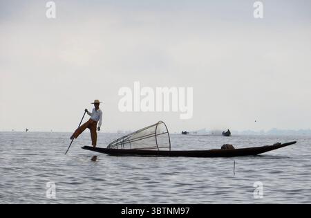 Les pêcheurs d'Intha naviguent habilement sur le lac Inle en utilisant leur technique unique d'aviron à jambes, une tradition séculaire qui incarne l'harmonie entre les PEO Banque D'Images
