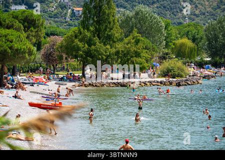 Torbole, Riva del Garda, Lac de Garde, Italie - 15 juillet 2025 : les touristes s'animent le long des rives du Lac de Garde entre Torbole et Riva. Soleil, eau et loisirs vous invitent à nager, jouer et vous détendre sur cette plage d'été populaire. *** Touristen tummeln sich am Ufer des Gardasees zwischen Torbole und Riva. Sonne, Wasser und Freizeit laden zum Schwimmen, Spielen und Entspannen an diesem Beliebten Sommerstrand ein. Banque D'Images