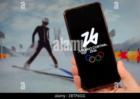 BOGOTA, COLOMBIE - 14 JUILLET 2025 Une main masculine tenant un smartphone avec le logo des Jeux olympiques d'hiver Milano Cortina 2026 et flou olympique saut à ski co Banque D'Images