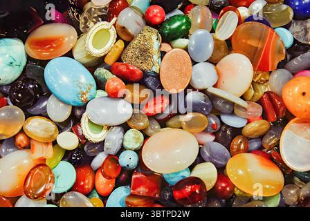 Pierres précieuses polies colorées assorties dans une vue rapprochée. Variété de formes, de textures et de couleurs vibrantes. Banque D'Images