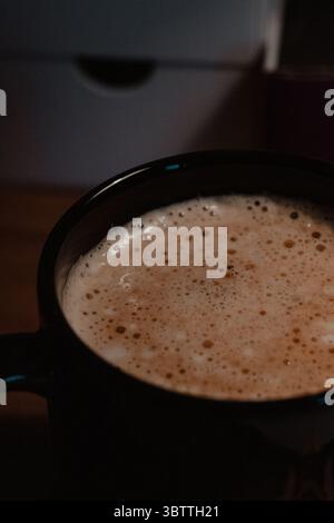 Gros plan du café Cappuccino dans une tasse noire Banque D'Images