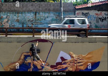27 novembre 2019, San Salvador, San Salvador, El Salvador : une voiture passe alors qu'un homme peint un graffiti sur le mur d'un passage supérieur dans la capitale du Salvador pendant la zone 503 : festival international des graffitis. (Crédit image : © Camilo Freedman/ZUMA Wire) Banque D'Images
