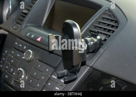 Gros plan de l'intérieur du tableau de bord d'une voiture montrant un support de smartphone fixé à la bouche d'aération. L'image met l'accent sur les accessoires de véhicules modernes, highlighti Banque D'Images