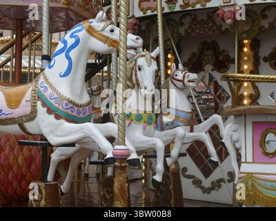 STRASBOURG, FRANCE - 27 MAI 2025 - chevaux de carrousel blancs aux décorations colorées se promenant sur un carrousel traditionnel Banque D'Images