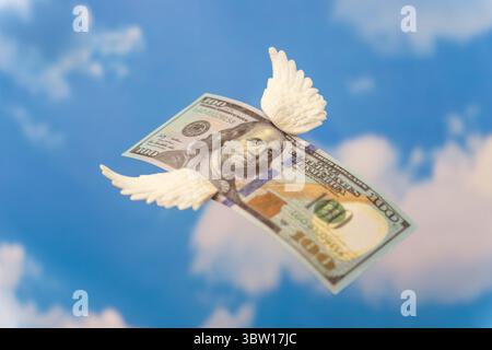 Un billet de cent dollars avec de petites ailes blanches. L'argent s'envole, concept de perte financière. Banque D'Images