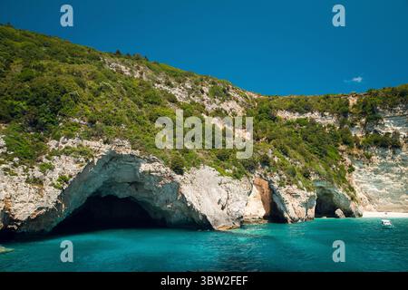 Un magnifique paysage côtier avec des falaises rocheuses et des eaux turquoises claires. La scène comprend des grottes naturelles le long du rivage, entourées de lu Banque D'Images