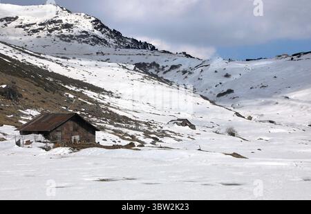 Un paysage de montagne enneigé serein avec une cabane en bois rustique. Le cadre paisible de l'hiver offre une évasion parfaite dans la nature intacte Banque D'Images