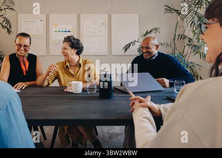 Membres professionnels de l'équipe discutant des stratégies et collaborant lors d'une réunion de projet productive dans un espace de travail moderne. Banque D'Images