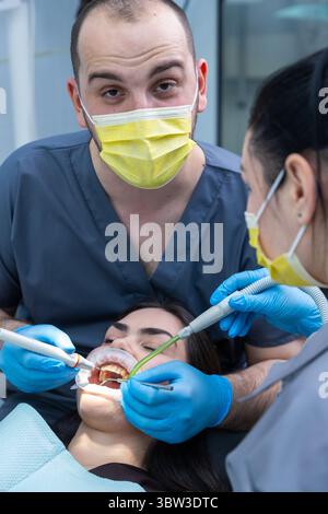 Soins dentaires en action : équipe professionnelle effectuant un traitement de routine avec des outils et techniques avancés pour le confort du patient et l'hygiène bucco-dentaire Banque D'Images