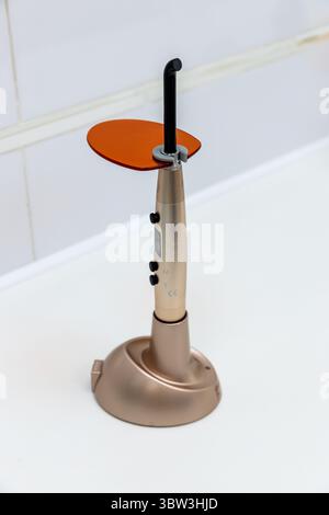 Outil avancé de lumière de durcissement dentaire pour les procédures dentaires et les traitements dans les cliniques modernes avec conception en or métallique et forme ergonomique pour Banque D'Images