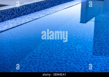 Piscine carrelée bleue avec une eau réfléchissante claire, présentant un design minimaliste et une atmosphère sereine, parfaite pour la détente ou l'architecte élégant Banque D'Images