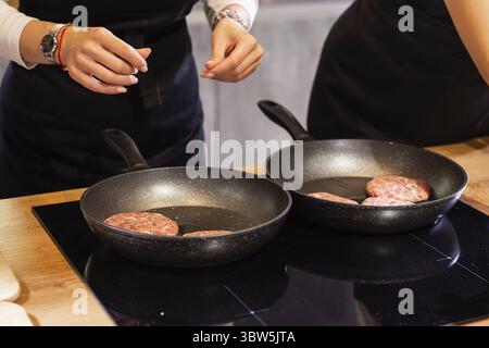 Hamburgers à la viande ou patty en forme de escalopes rôtisant dans l'huile sur une poêle gros plan Banque D'Images