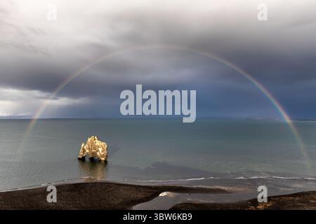 Vue de la formation rocheuse de Hvítserkur s'élevant majestueusement de la mer sombre, couronnée par un arc-en-ciel vibrant sous un ciel spectaculaire, Islande, , Islande. Banque D'Images