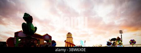 Sculpture de grenouille verte perchée sur la plate-forme du champ de foire dans un design plat avec tour de toboggan rayé Banque D'Images