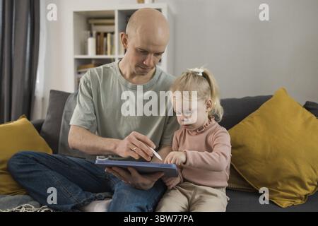 Enfant sourd fille avec implant cochléaire étudiant pour entendre les sons et s'amuser avec son père - récupération après chirurgie d'implant cochléaire et réadaptation co Banque D'Images