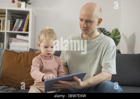 Enfant sourd fille avec implant cochléaire étudiant pour entendre les sons et s'amuser avec son père - récupération après chirurgie d'implant cochléaire et réadaptation co Banque D'Images