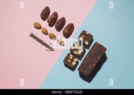 Barres de bonbons aux fruits à la date des protéines fitness avec fruits à coque et amande et graines de chia et de pavot, vue du dessus sur fond rose bleu avec espace et lieu de copie Banque D'Images