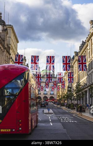 Une scène londonienne classique avec un bus rouge, des drapeaux Union Jack et une architecture historique dans une rue animée de la ville Banque D'Images