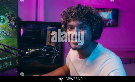 Joyeux homme indien arabe latino heureux homme dans les écouteurs gars souriant riant streamer joueur tapant clavier influenceur diffusion blogueur vlogger Banque D'Images