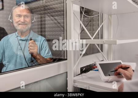 Un homme âgé se faisant passer un test auditif au centre d'audiologie. Audiométrie, bilan auditif Banque D'Images
