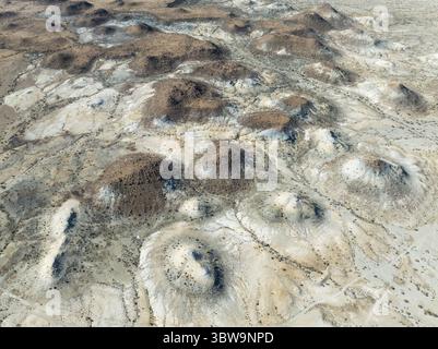 Vue aérienne de paysages arides parsemés de mesas isolés et altérés projetant des ombres sur la terre pâle, créant un contraste saisissant de lumière et de texture, Keetmanshoop, région de Karas, Namibie. Banque D'Images