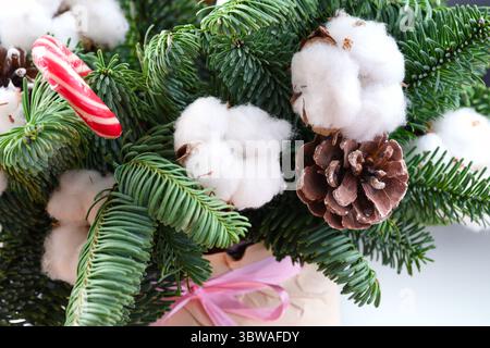 Composition florale d'hiver de Noël avec des fleurs de coton, des branches d'épicéa, des cônes d'épicéa et de la canne à bonbons. Gros plan Banque D'Images